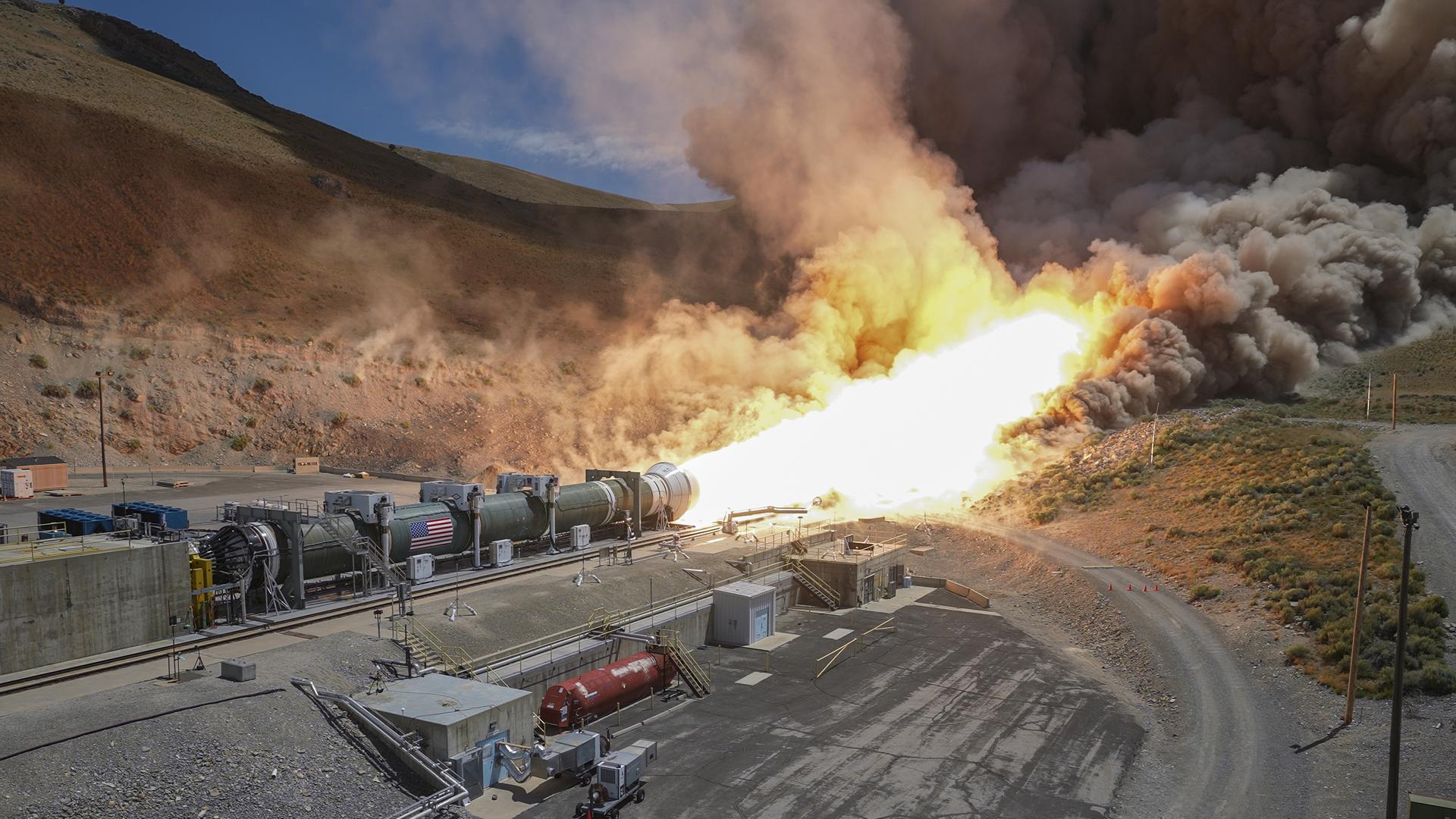 A giant flame spews horizontally from a metal cylinder.