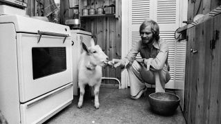 Long John Baldry in his kitchen feeding a goat