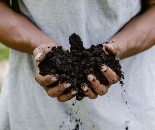 A pair of hands holding a pile of fresh soil