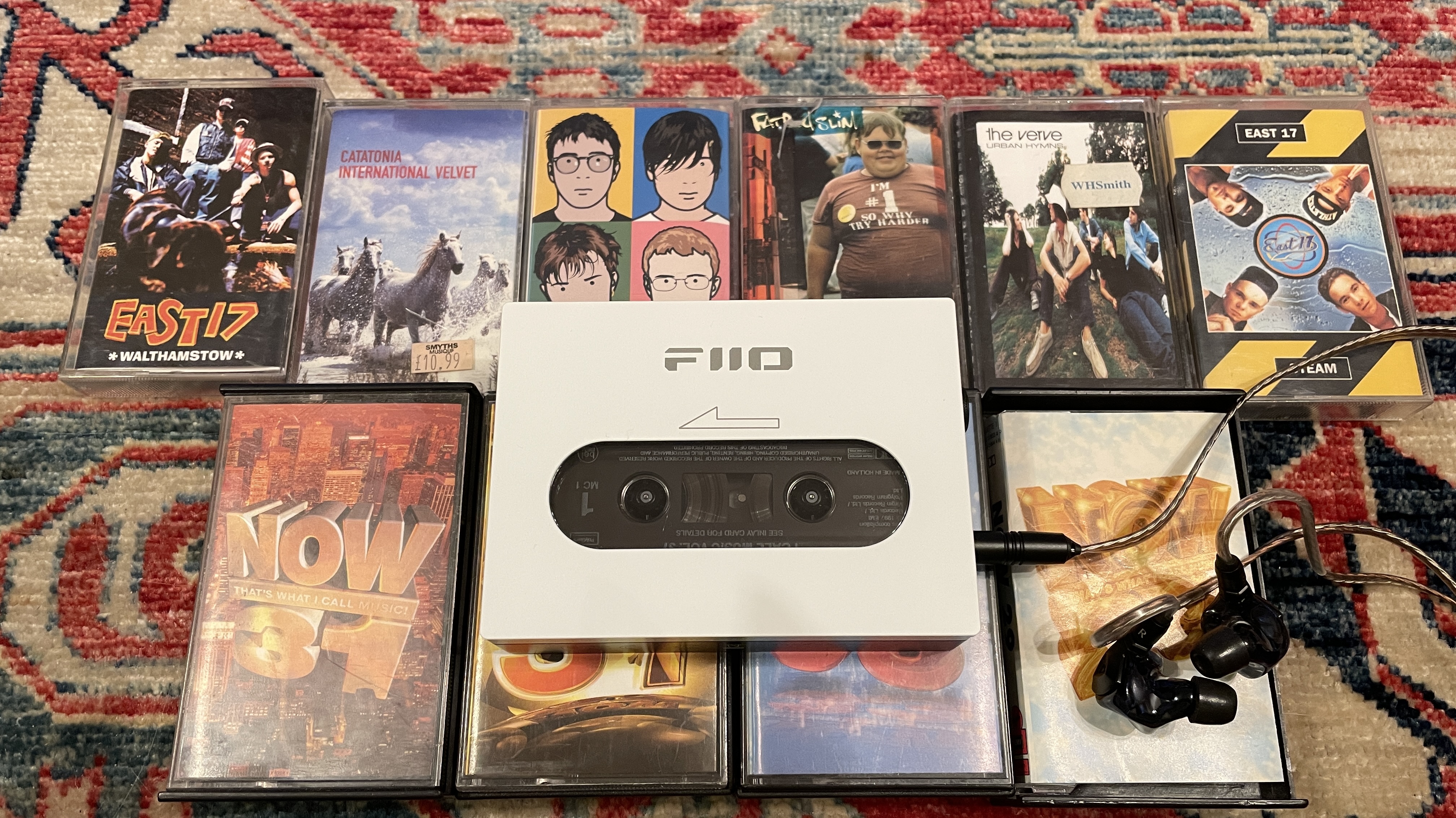 FiiO's CP13 with Campfire Audio Clara IEMs, on top of several cassette tapes, all on a colorful carpet