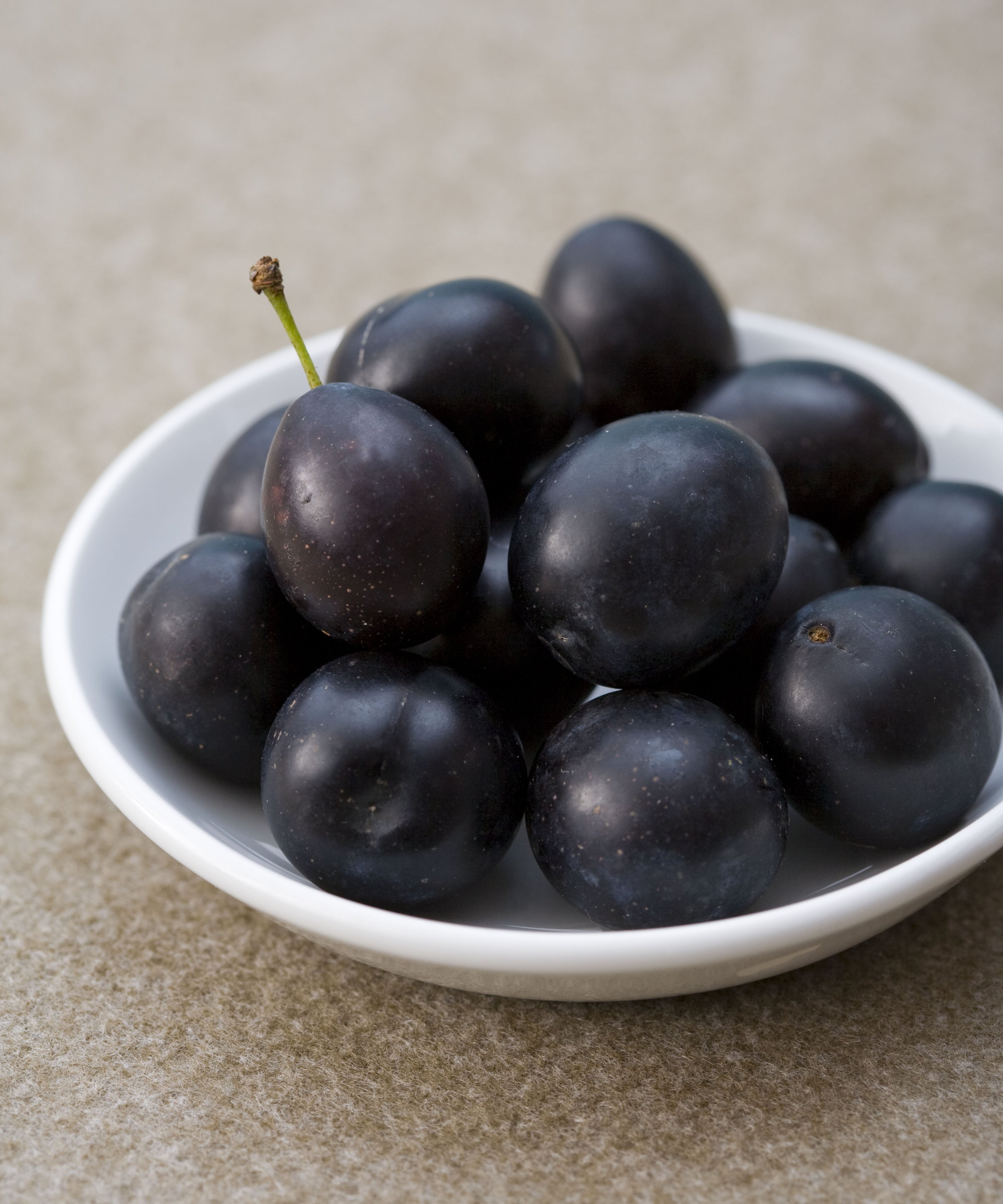Dark damson fruits in a white bowl