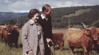 Queen Elizabeth II and Prince Philip in a field with some highland cattle