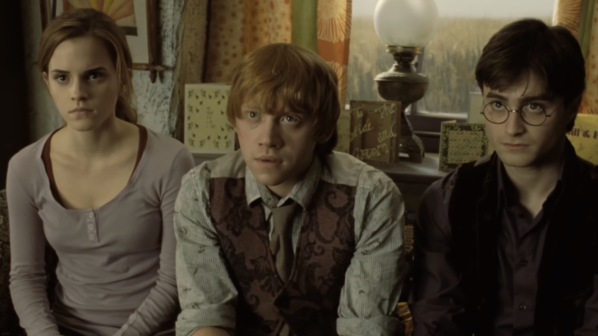 Hermione, Ron, and Harry sitting listening to Rufus Scrimgeour in Deathly Hallows: Part 1.