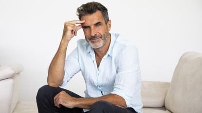 A recently retired guy sits on a couch, considering going back to work.