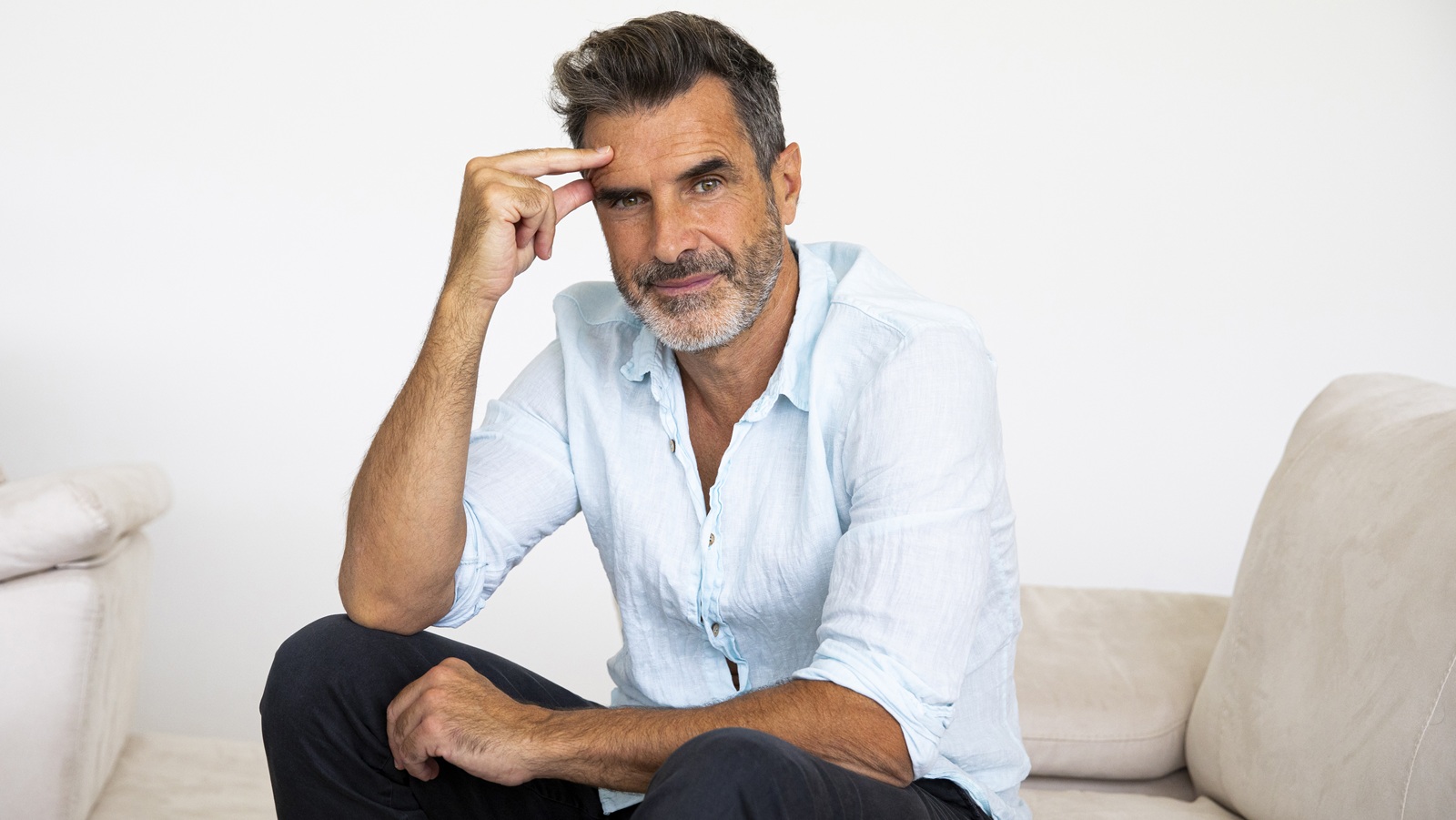 A recently retired guy sits on a couch, considering going back to work. 