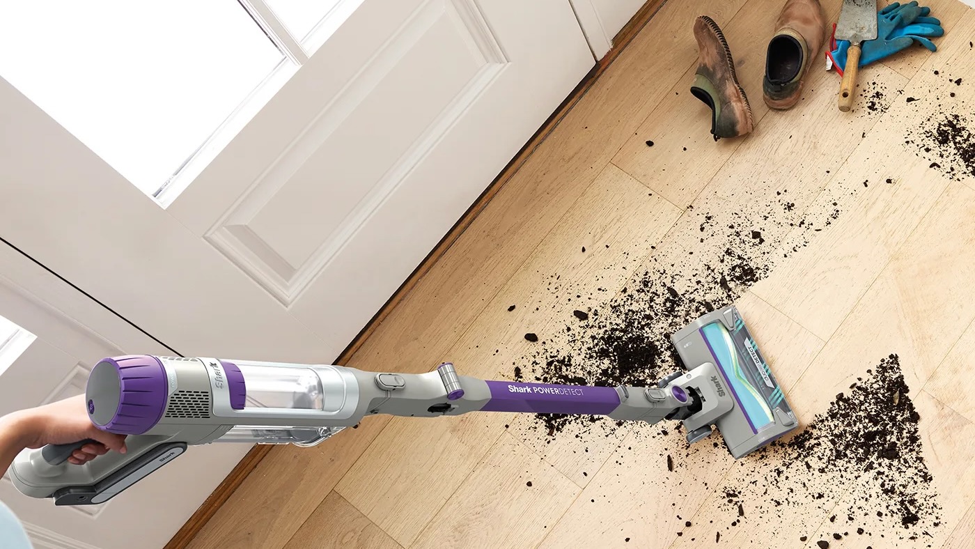 Person cleaning dirt with Shark PowerDetect Cordless vacuum on wood floor