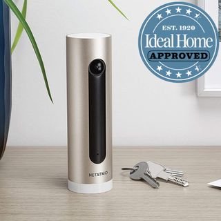 Netatmo Smart Indoor Security Camera with a pair of keys on the desk next to it and Ideal Home approved badge