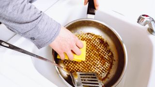Cleaning a dirty pan in the sink