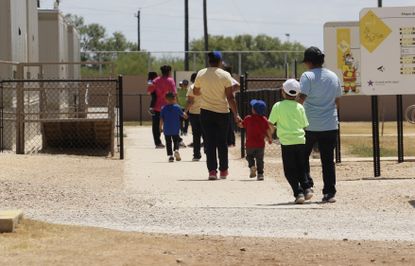 Immigrants seeking asylum hold hands as they leave a cafeteria at the ICE South Texas Family Residential Center in Dilley, Texas.