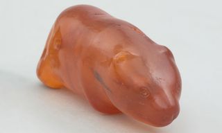 A carved amber bear figurine against a white background