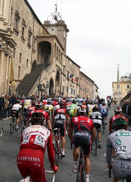 The peloton riding past the scenic piazza in Tarquinia.