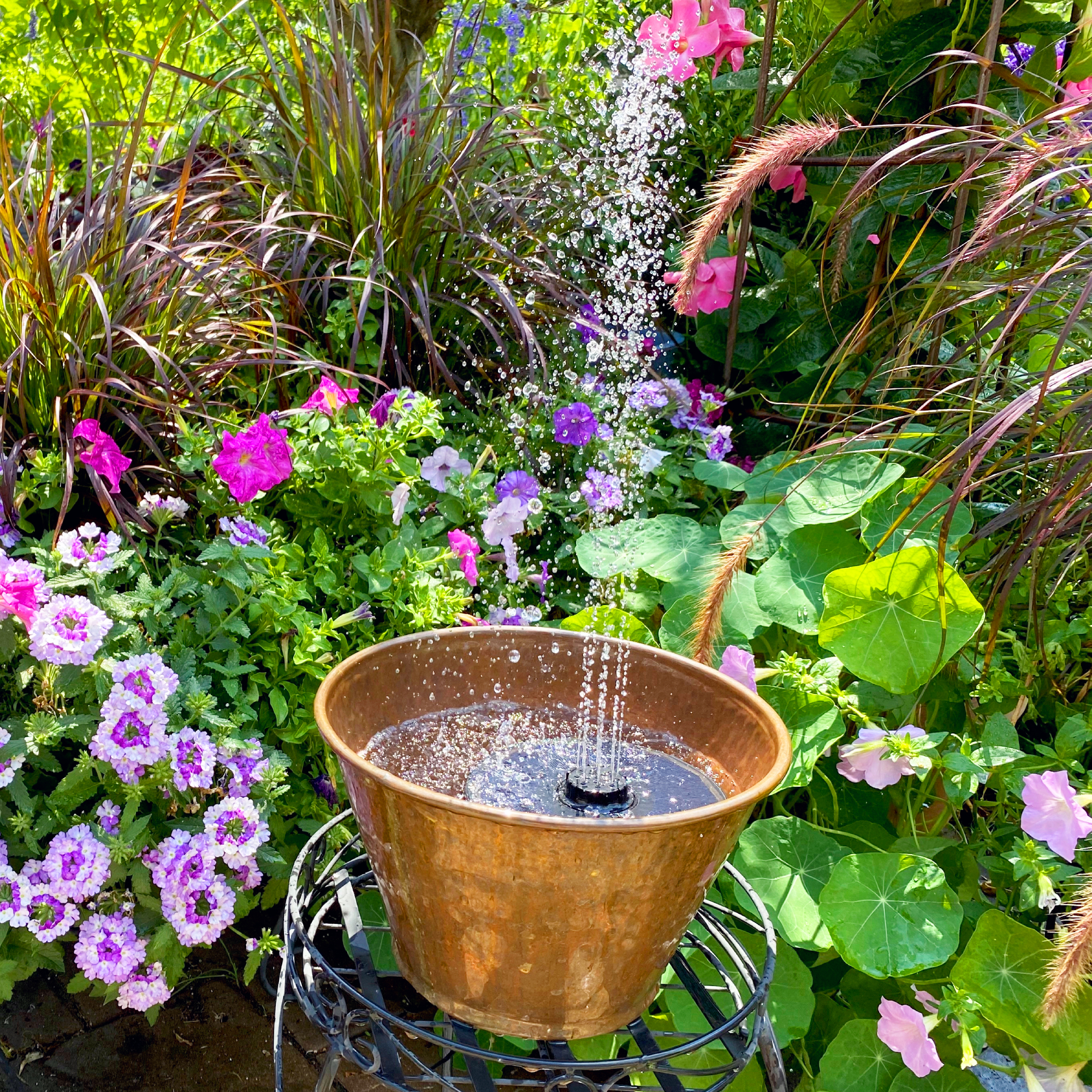 Garden water feature made from a container and a solar powered floating water fountain