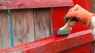 A painter painting wooden fence