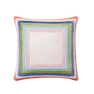 A multicolor throw pillow with 60s colors around the trim and a pink center