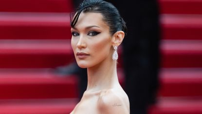 Bella Hadid wearing a low cut strapless dress on a red carpet to illustrate a story about her nearly naked Orebella dresses