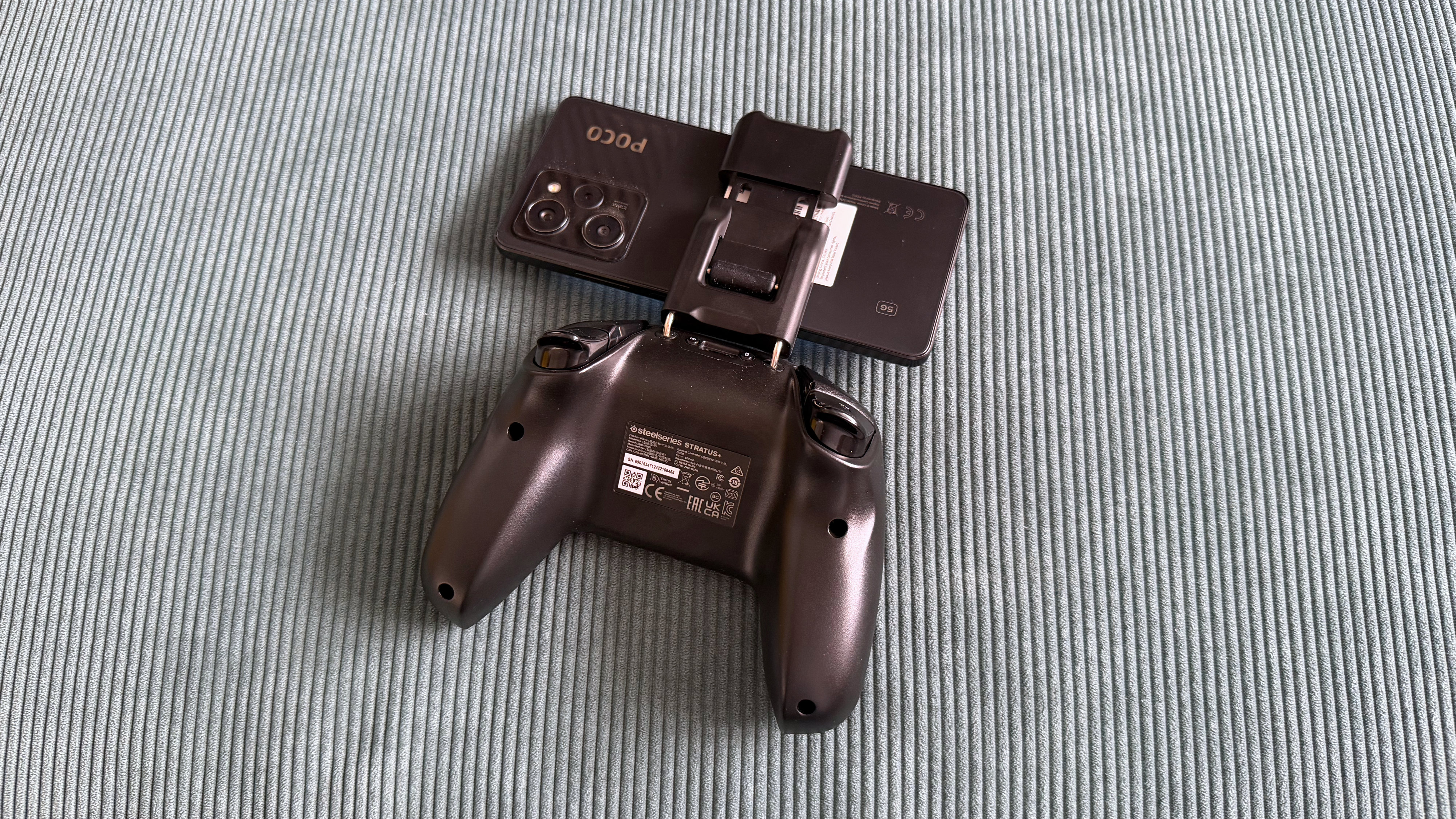 The SteelSeries Stratus+ mobile and PC controller on top of a green carpet surface
