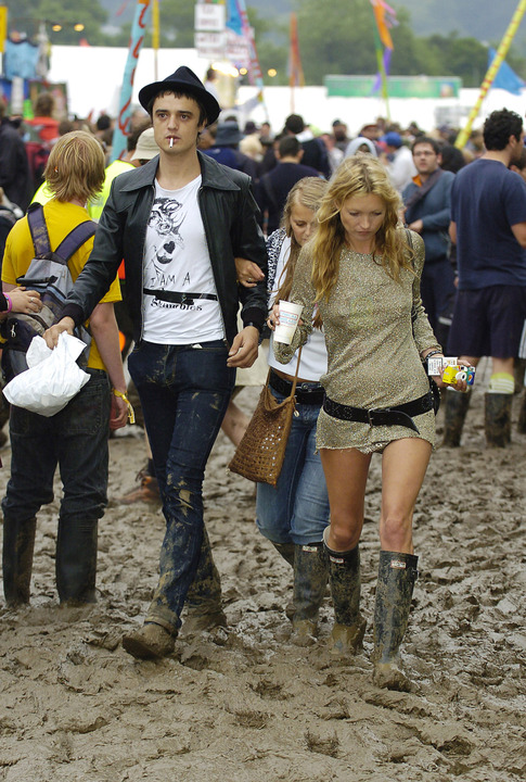 Kate Moss in a gold dress hunter wellies and Western belt at Glastonbury festival in an image from Getty taken in 2005.