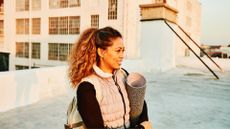 Woman holding her yoga mat and smiling after doing jack plank exercise in autumn sunshine on a rooftop