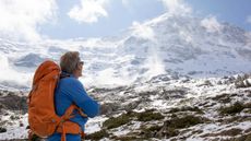 Male hiker looks off to misty, snow covered mountain peaks