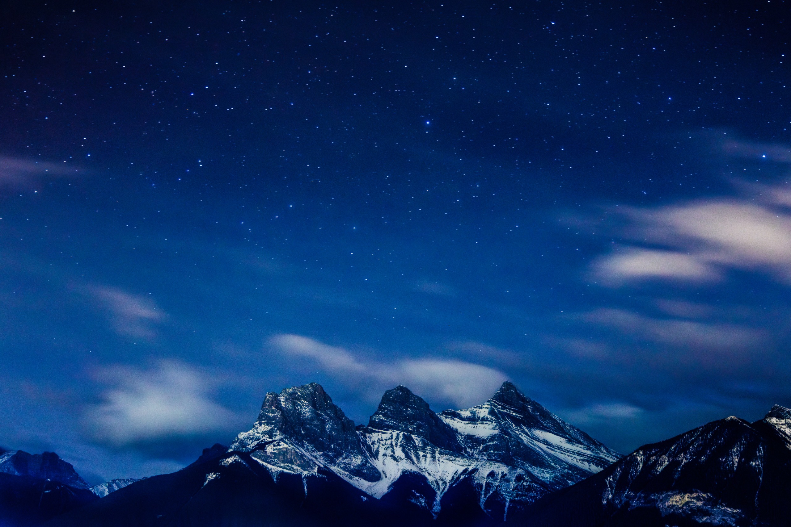 A view of the Three Sisters Mountains and the surrounding peaks, along with the stars in the sky above Canmore, Alberta, Canada, on November 12, 2025.