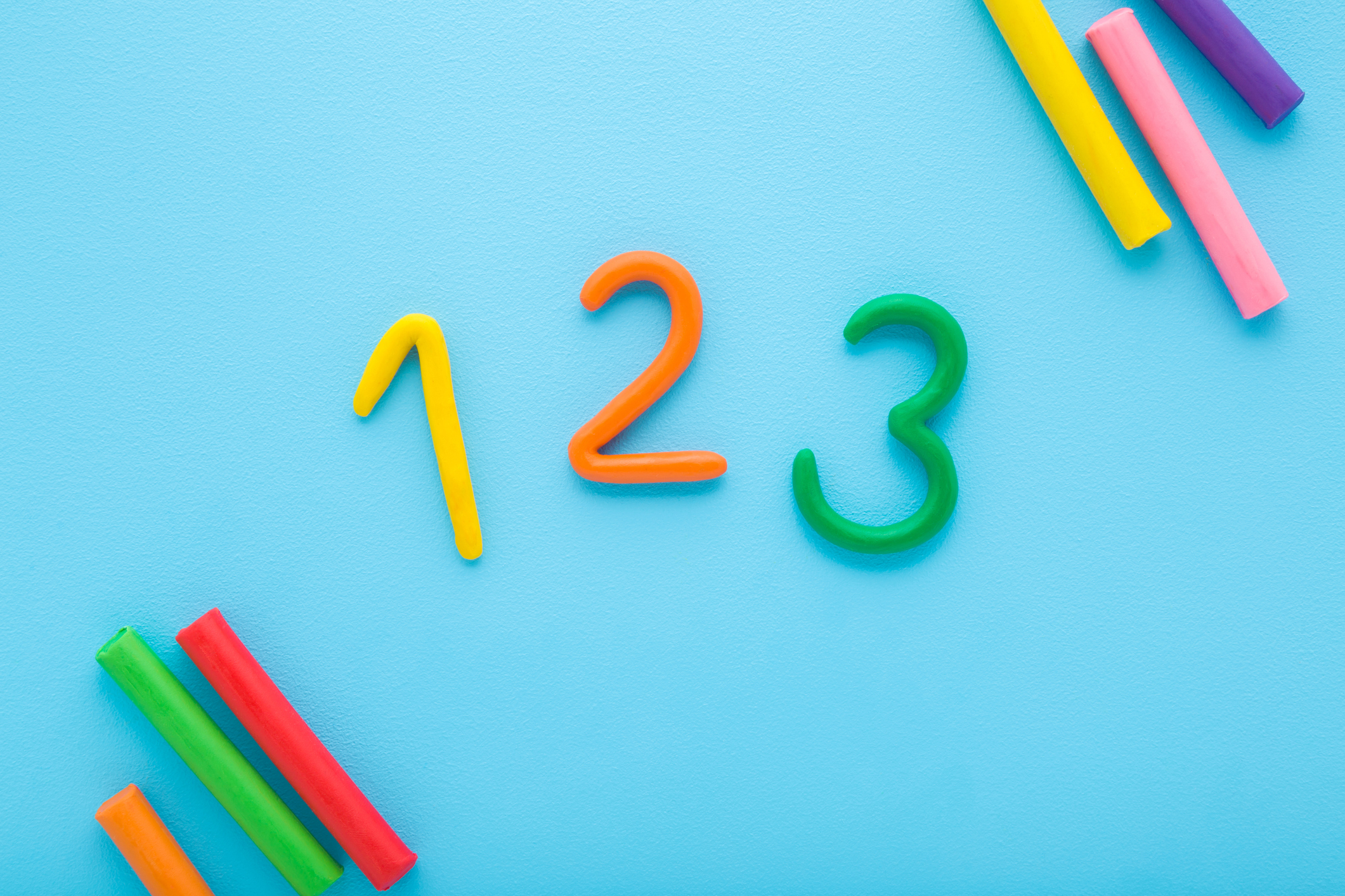 Colorful 123 numbers created from modeling clay on light blue table background. 