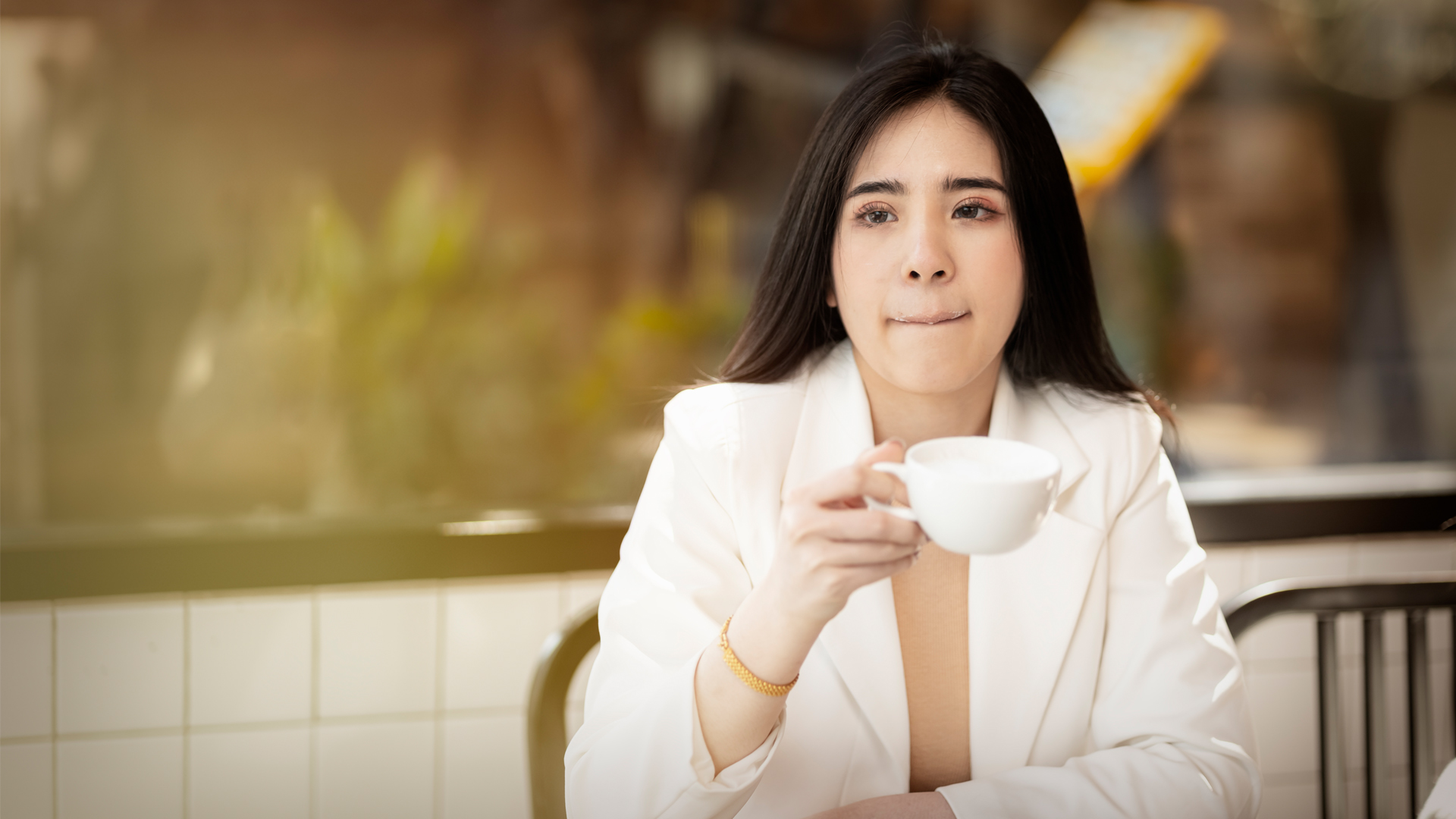 Image of woman pursing her lips as she drinks coffee