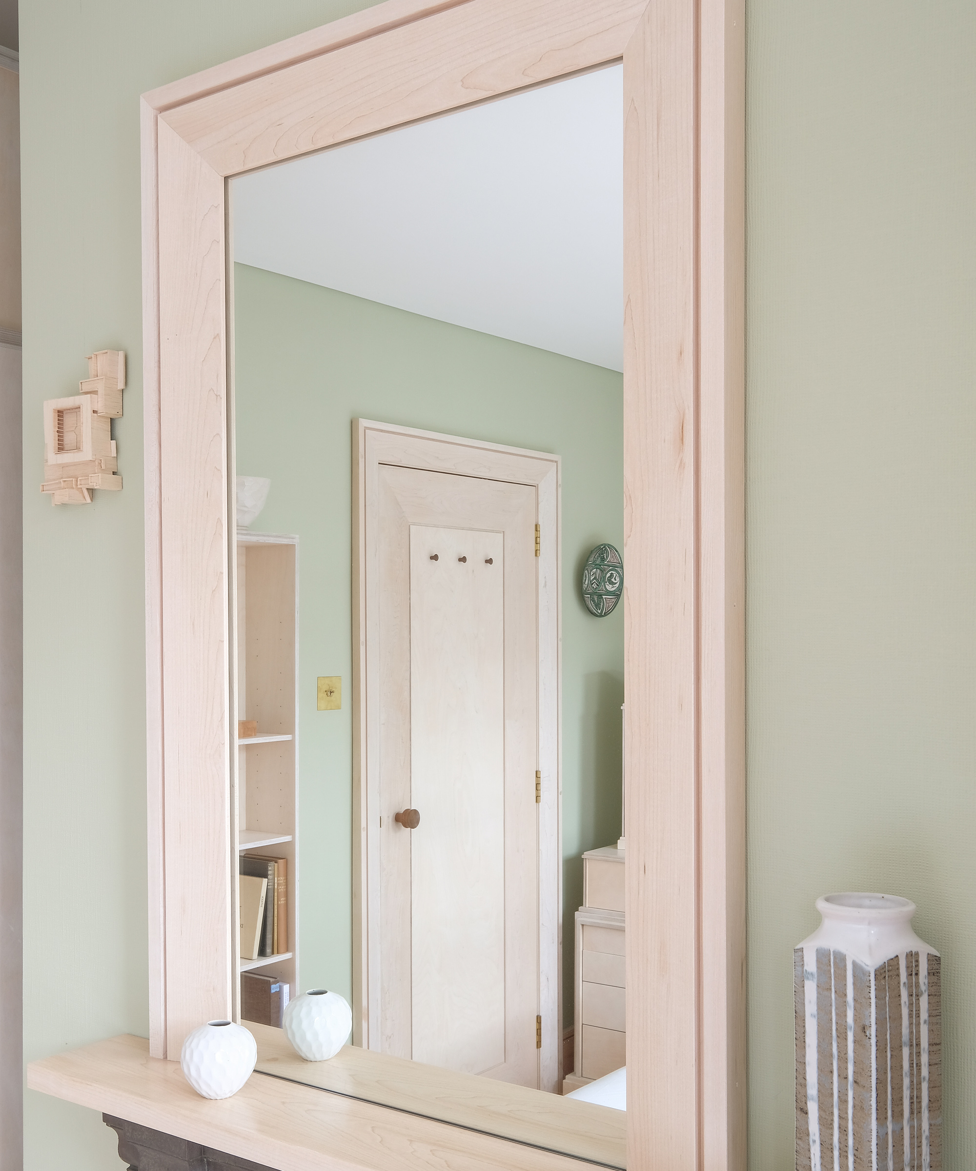 A plywood framed mirror above a fireplace