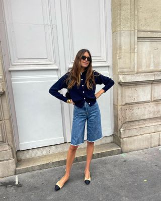 French woman in cardigan and bermuda shorts.