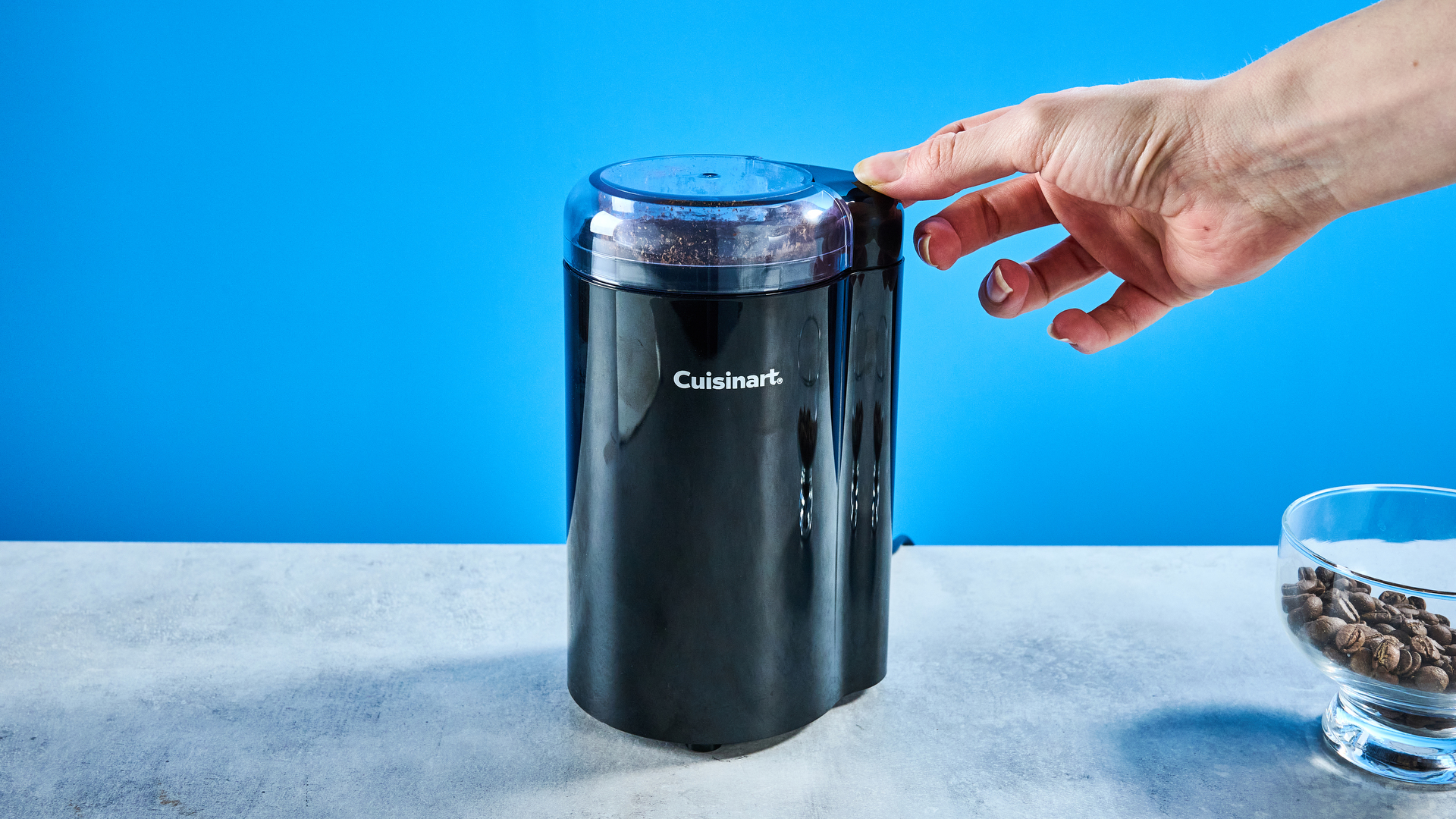 the cuisinart coffee grinder photographed against a blue background showing its blades and canister