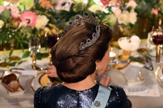 The back of Queen Silvia wearing a blue sequin gown wearing an updo and a diamond and sapphire tiara