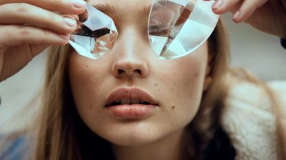 Face shot of woman covering eyes with glass crystals - stock photo