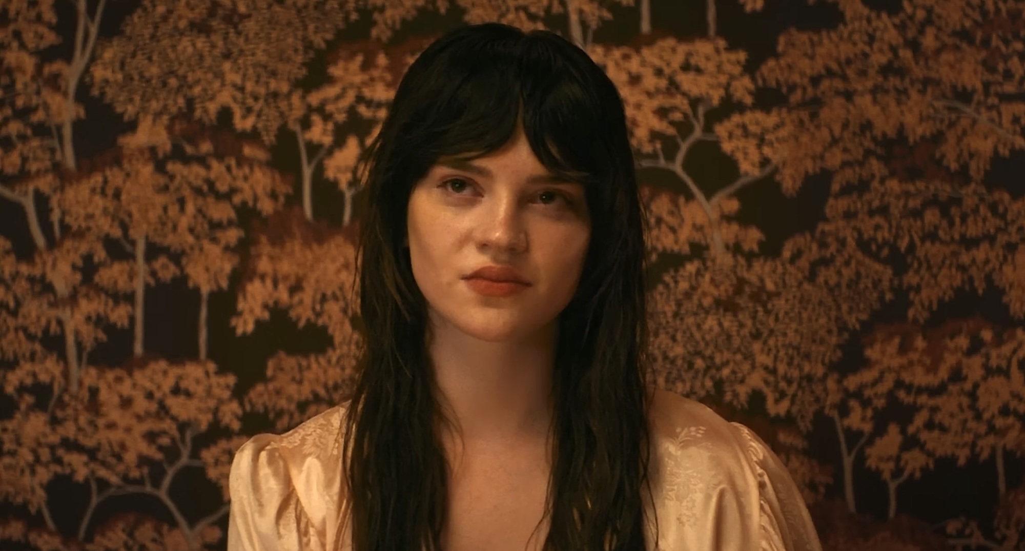 Elle sitting against backdrop of trees with yellow leaves in Her Private Hell