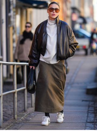 A woman wearing a long skirt, black tights and trainers