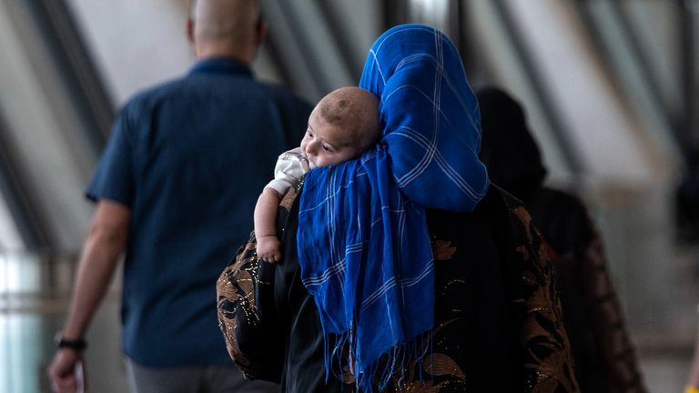 Afghan woman and child refugees are escorted to a waiting bus after arriving at Dulles International Airport
