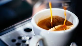 Espresso shot pouring into ceramic cup