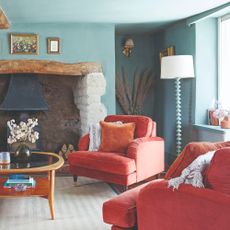 A blue-painted living room with a tonal bobbin floor lamp and a two coral velvet armchairs