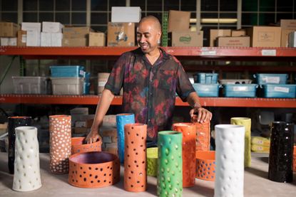 A portrait of designer Stephen Burks in the ceramics workshop at Berea College, surrounded by colourful ceramic vases