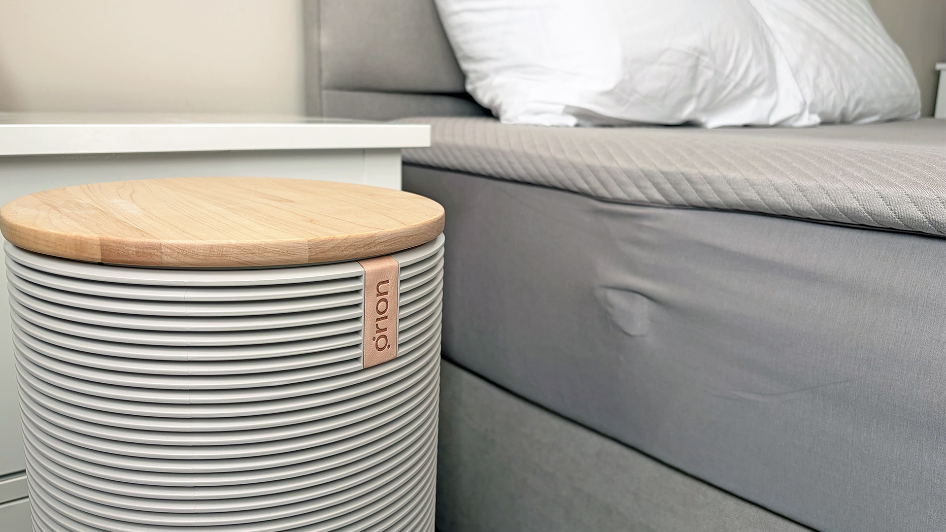 A close up of the Orion Sleep System Control Tower next to the Orion mattress cover on a bed in our reviewer's room
