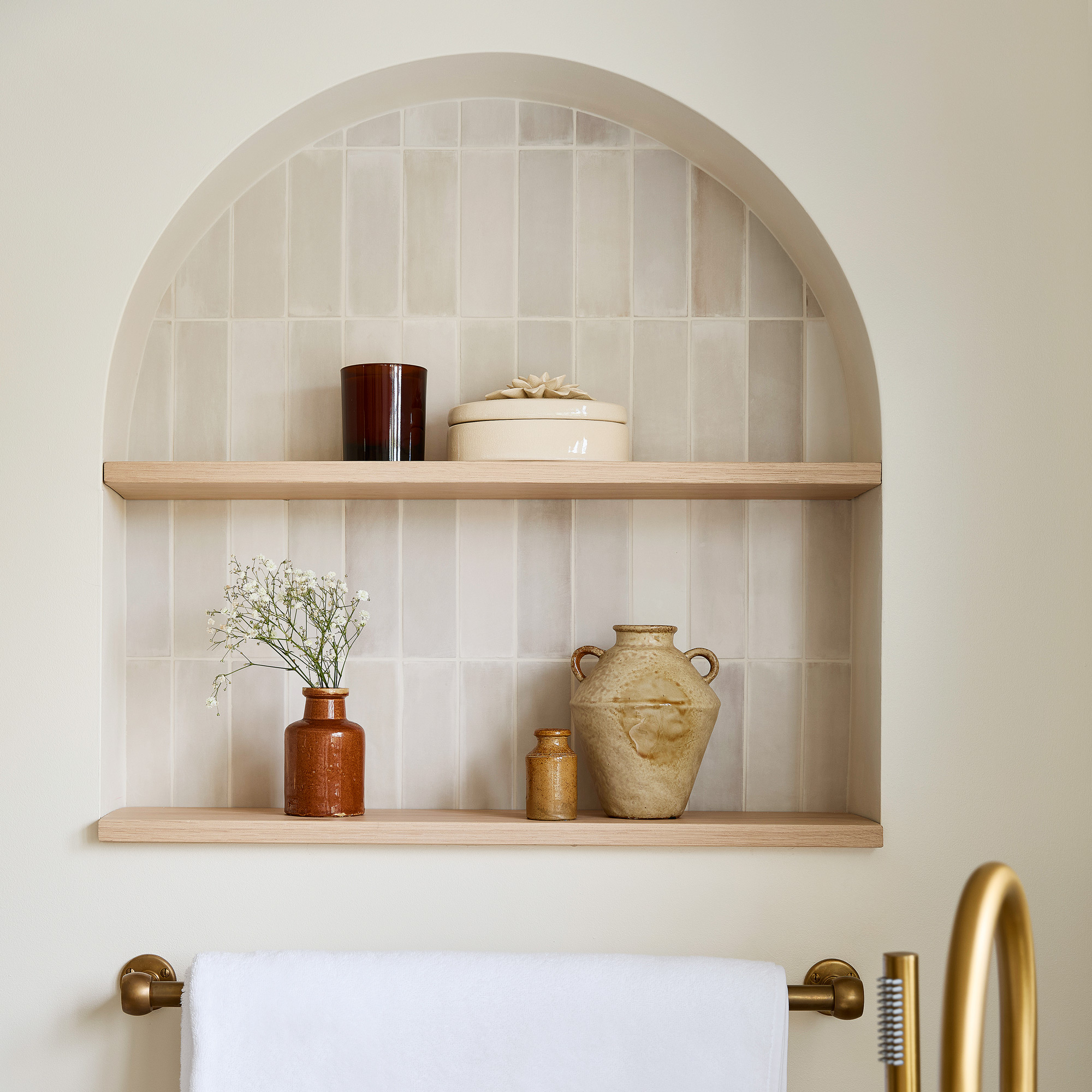 a neutral bathroom with a recessed, tiled shelving space