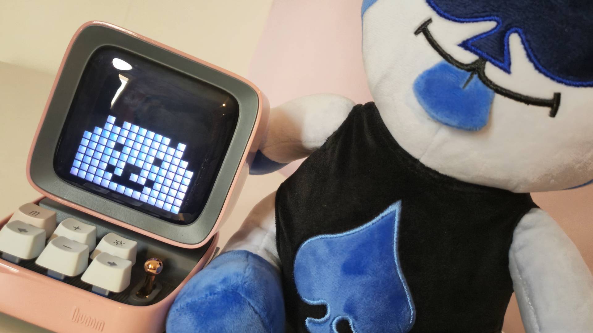 Photo by Rosalie Newcombe of the Divoom speaker sitting next to the Fangamer Lancer plushie from Deltarune.