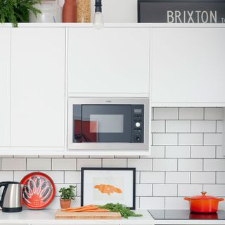 kitchen with white cabinet and microwave with white wall tiles