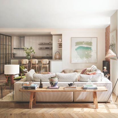 Open plan living room and kitchen with neutral woods, wooden flors and grey sofa