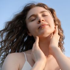 A woman with clear skin holding her face