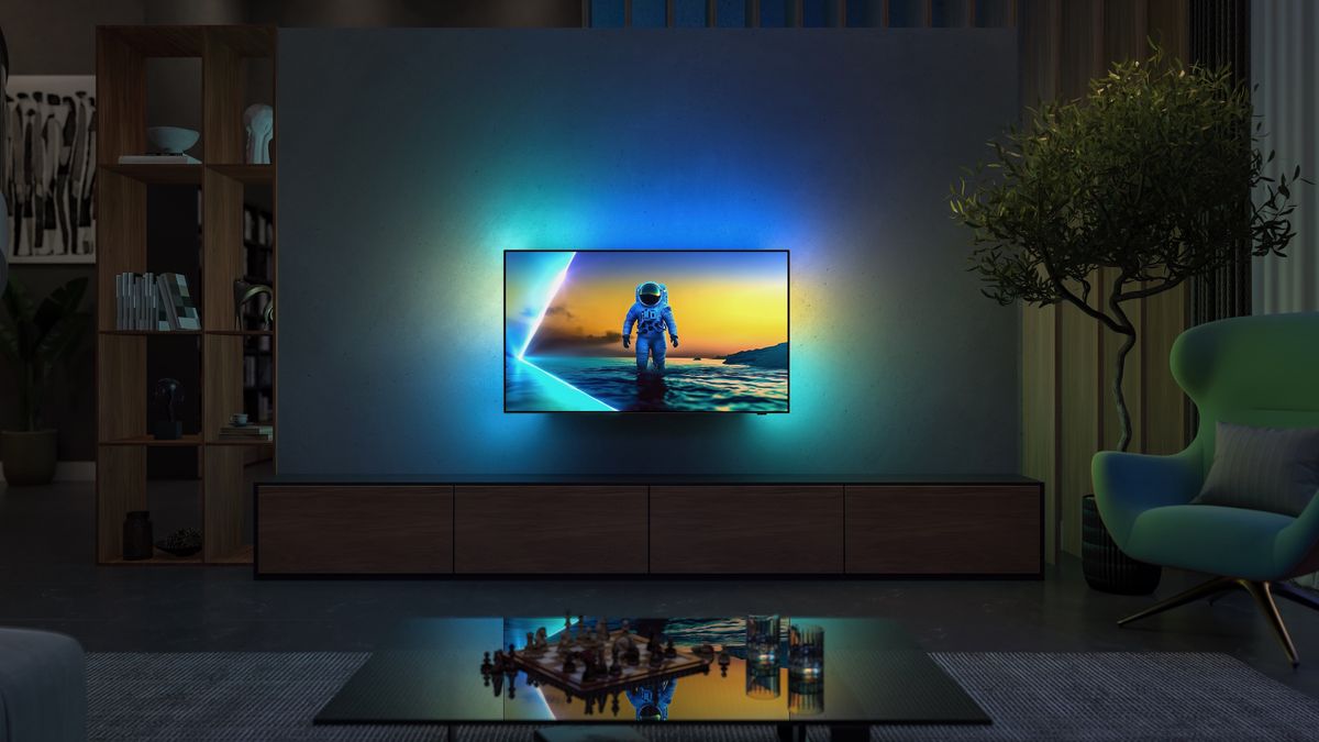 A Philips OLED810 TV wall-mounted in a high-end lounge. On screen is an astronaut on a planet, with Ambilight spilling the same-coloured light onto the wall behind it.