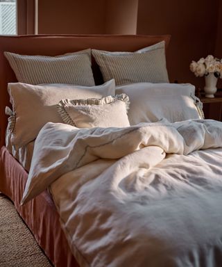 Rustic cream linen bedding in an unmade red upholstered bed