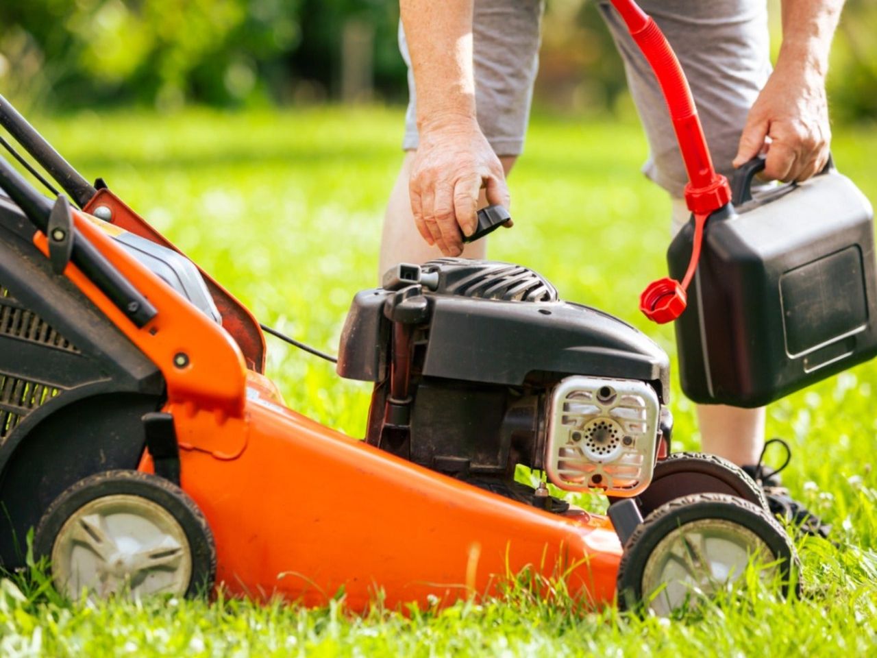 A man adding gasoline to a lawnmower