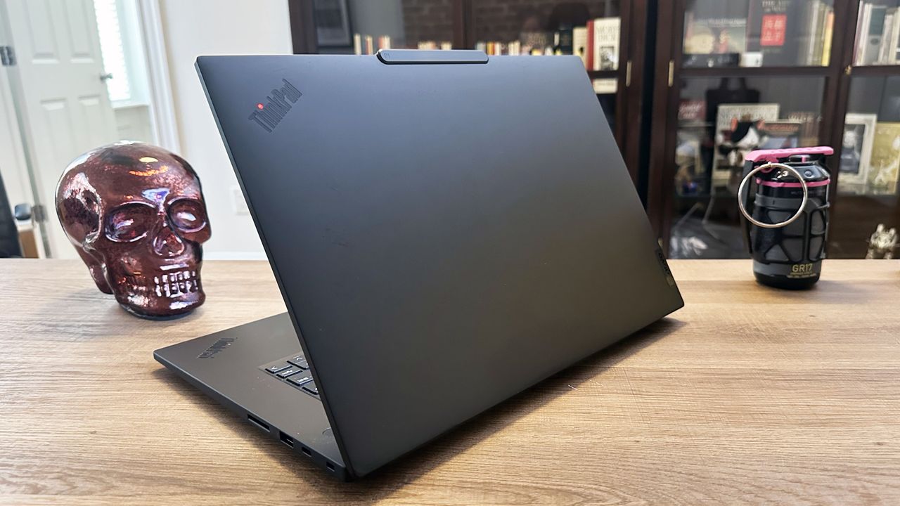An open, black laptop angled on top of a wooden desk.