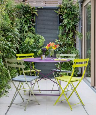Small sheltered patio garden. A living wall with plants and a garden table and chairs