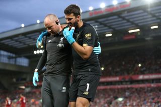 Alisson Becker, right, is helped off the pitch against Norwich