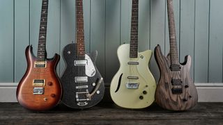 Four baritone guitars against a wooden wall